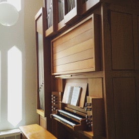 An organ beside sunny windows
