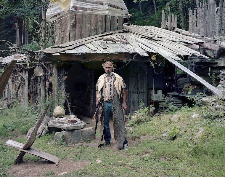 A person in front of a roughly built home.