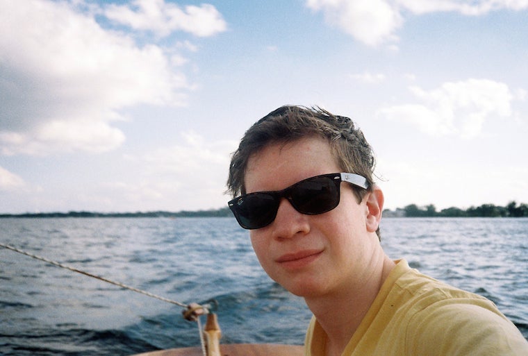 Student looks at the camera wearing sunglasses. He appears to be on a boat in the middle of a lake