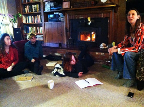Students in front of a fireplace with notebooks.