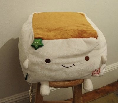A beanbag pillow looks like tofu with a face and limbs.