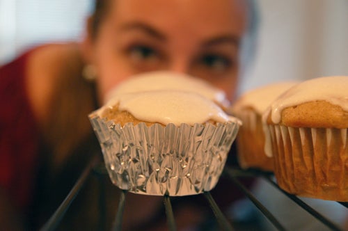 A girl peers over an iced cupcake