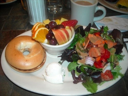 a plate of fruit, salad, and a bagel