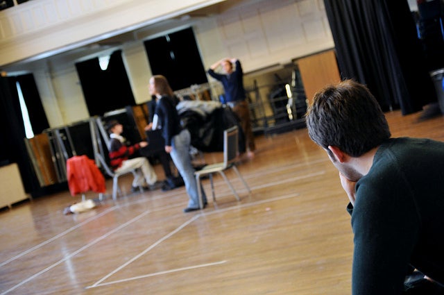 A student watches others rehearse 