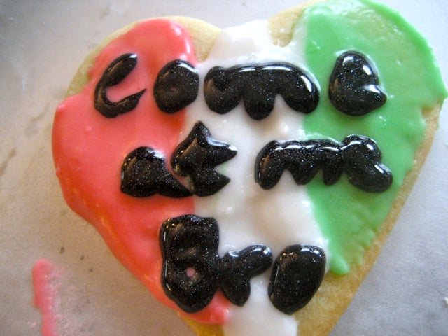 A heart shaped cookie with red, white, and green stripes and the words "come at me bro"