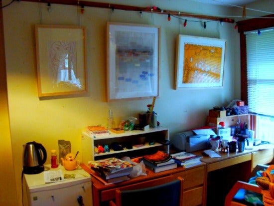 Three artworks hang above a desk. 