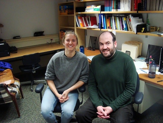 Student posing for photo with professor in an office