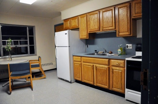 Kitchen with fridge, stove, sink, cabinets, table, and chairs.
