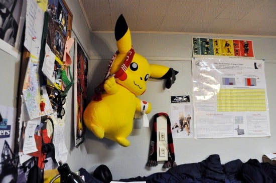 A giant Pikachu character lords over this room. The bulletin board is covered in papers.