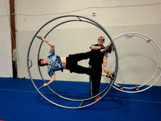 Will in a circus wheel with his body parallel to the floor