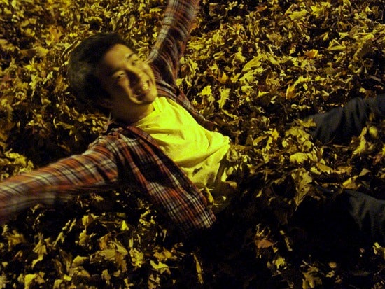Student laying in a pile of leaves 