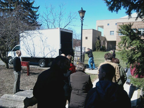 People watch the letter carrier being wheeled into the semi-truck