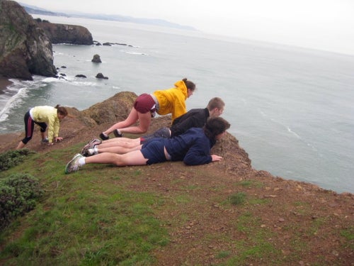 Students peer over a ledge of a cliff