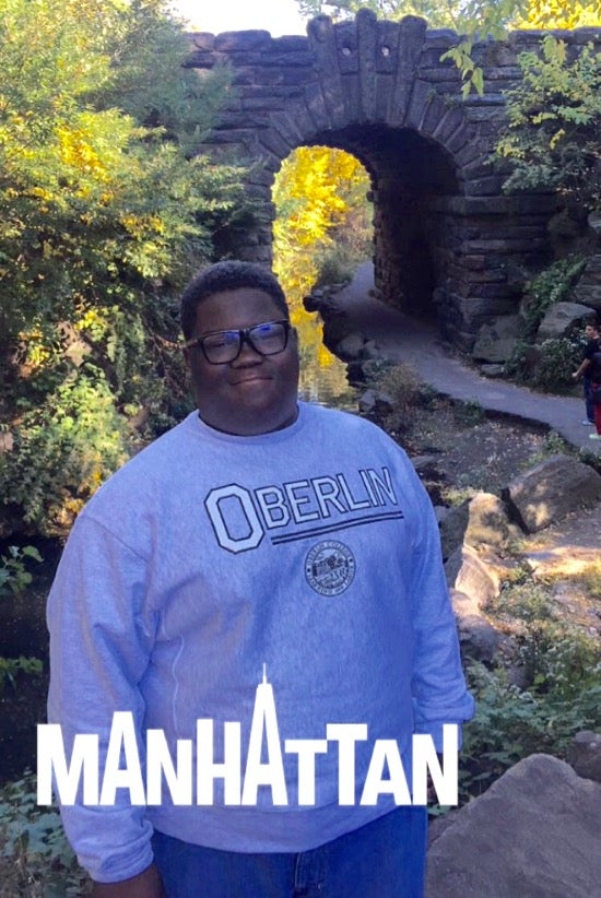 Kameron by a stone bridge. A graphical overlay says Manhattan.
