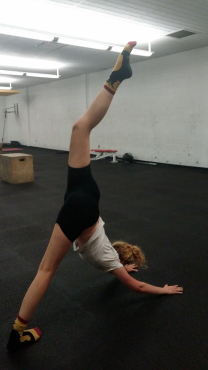 Karalyn stretches, face-down with hands on the mat and one leg raised high