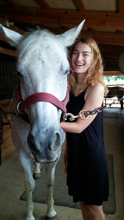 Karalyn stands next to a white horse inside the barn