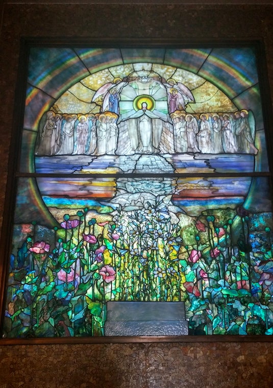 Stained glass scene of Christ with disciples above a field of flowers