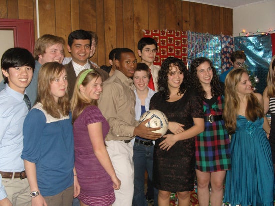 Group of students smiling for a picture wearing formal attire. One holds a soccer ball