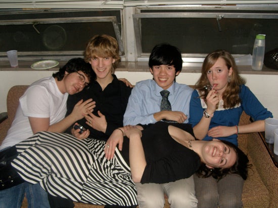 four of the students sit on a couch with one student laying on their laps