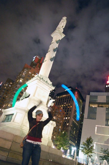 A student spins poi in front of a monument