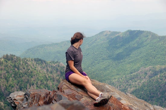A student overlooks a cliff above mountain tops