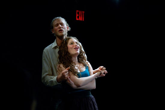 A performer holds another performer in their arms at the revue