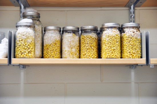 Jars on a shelf filled with yellow things that look like corn kernels