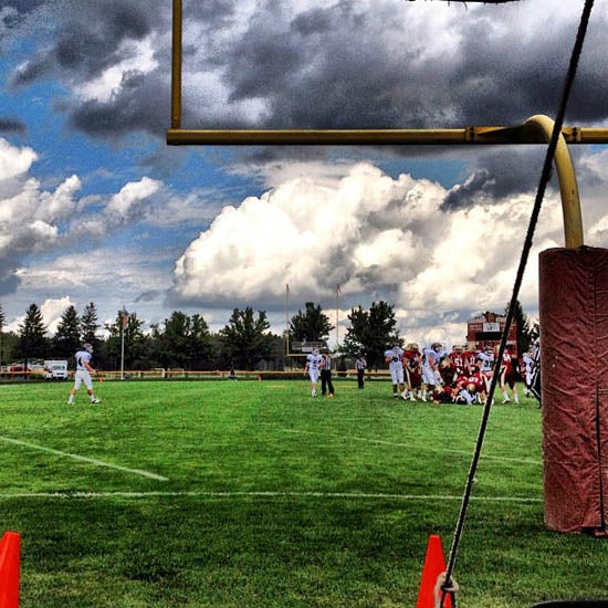 Large clouds over a football team practicing 