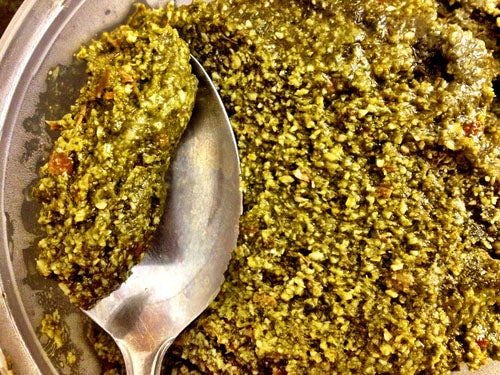 Close up of a spoon in pesto sauce
