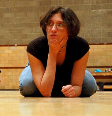 Kneeling on a gym floor, Amanda leans forward on her elbow.