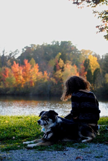A girl sits with a dog in the arb