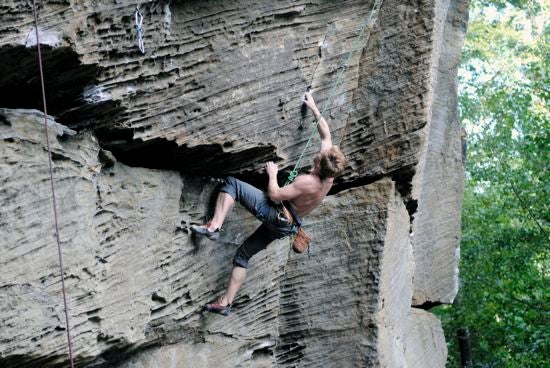 A climber rock climbing on a real-life rock wall 