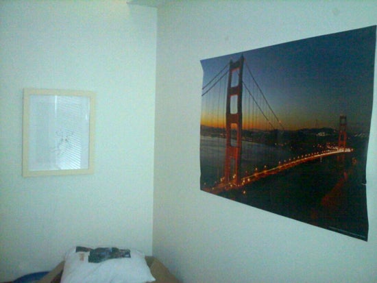 A poster of the golden gate bridge hung above a bed