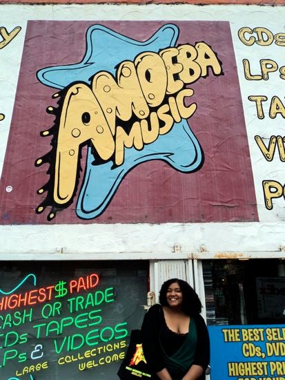 Someone posing for a photo in front of an "Amoeba Music" logo 