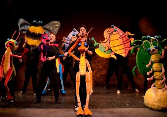 Students on stage holding bug puppets
