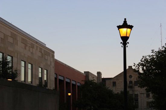 A glowing lamp post near campus buildings