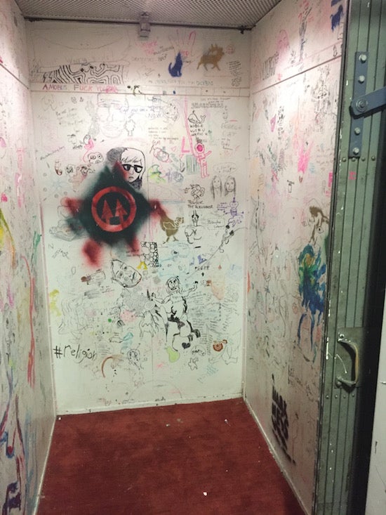 Walls of an old elevator are covered in drawings and graffiti-like writing