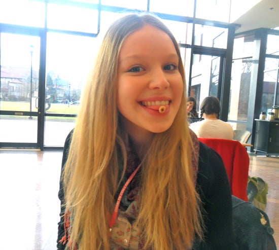 A student sitting in the Science Center with a cheerio stuck to her tongue