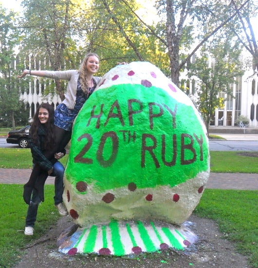 A student holds another in front of the rock