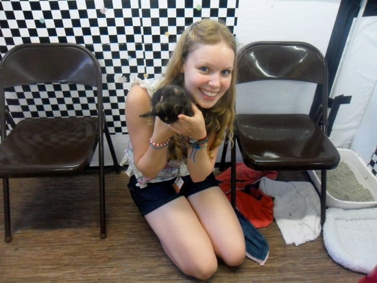 A student poses with a kitten in her hands