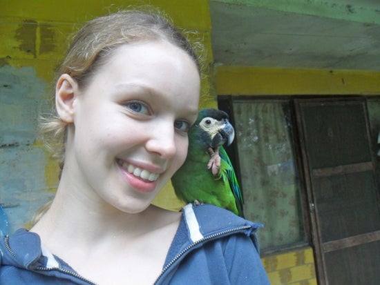 A student poses for the photo with a parrot on their shoulder
