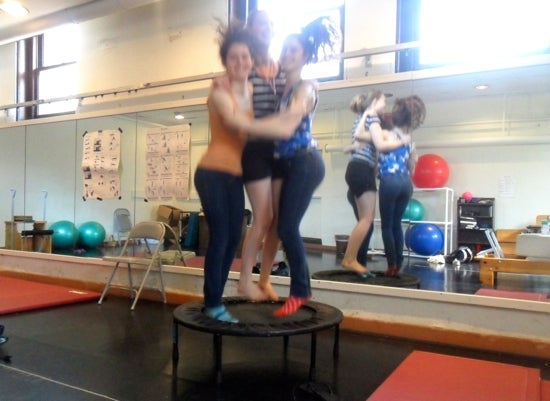 Three students embracing mid jump on a trampoline