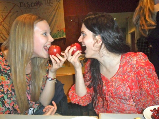 Two students staring into each others eyes as they bite into apples