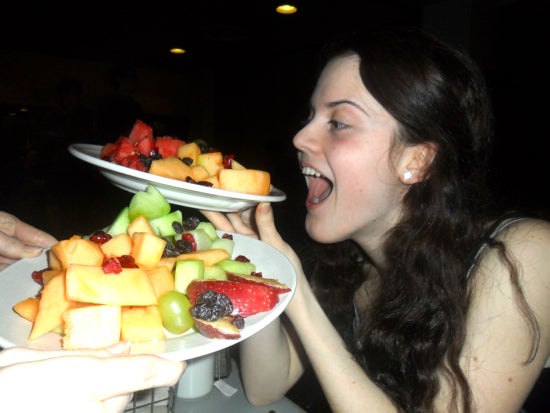 A student poses with her mouth open holding a plate of fruit
