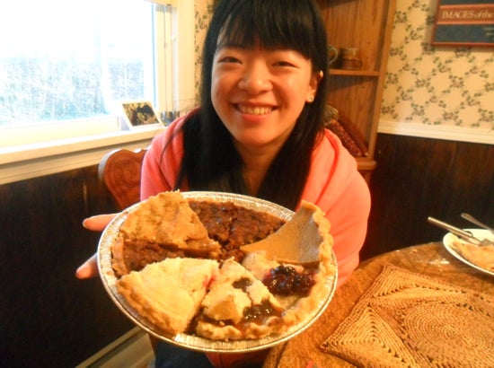 A student holds up a pie tin filled with different kinds of pie pieces 