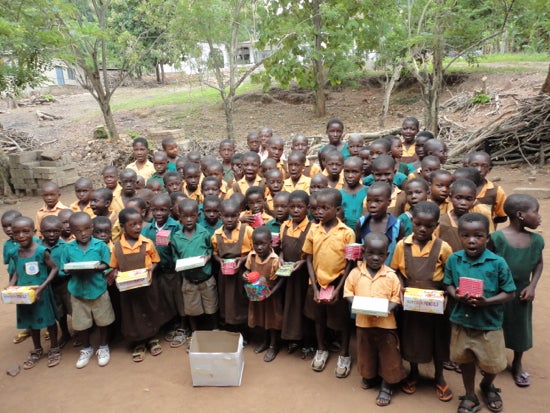 A group of children in uniforms holding small boxes 