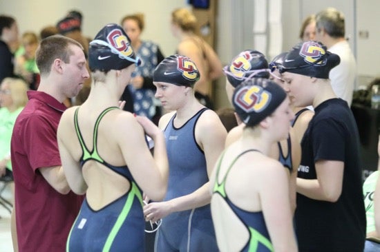 A group of Oberlin swimmers poolside wearing their swimming gear and swim caps