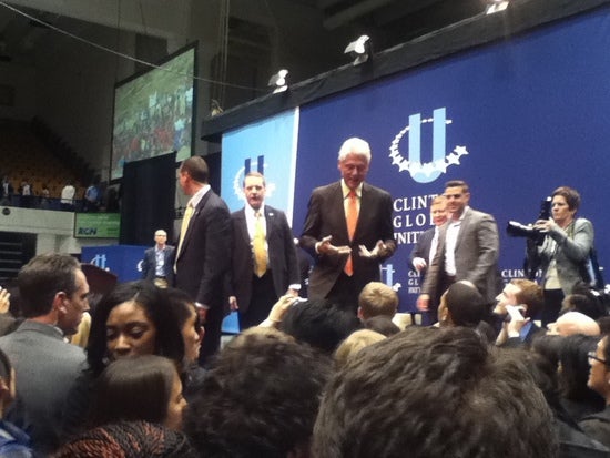 Bill Clinton stands on the CGIU stage and speaks informally with the audience.