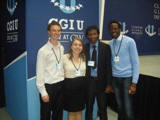 Four students in front of CGIU conference signage.