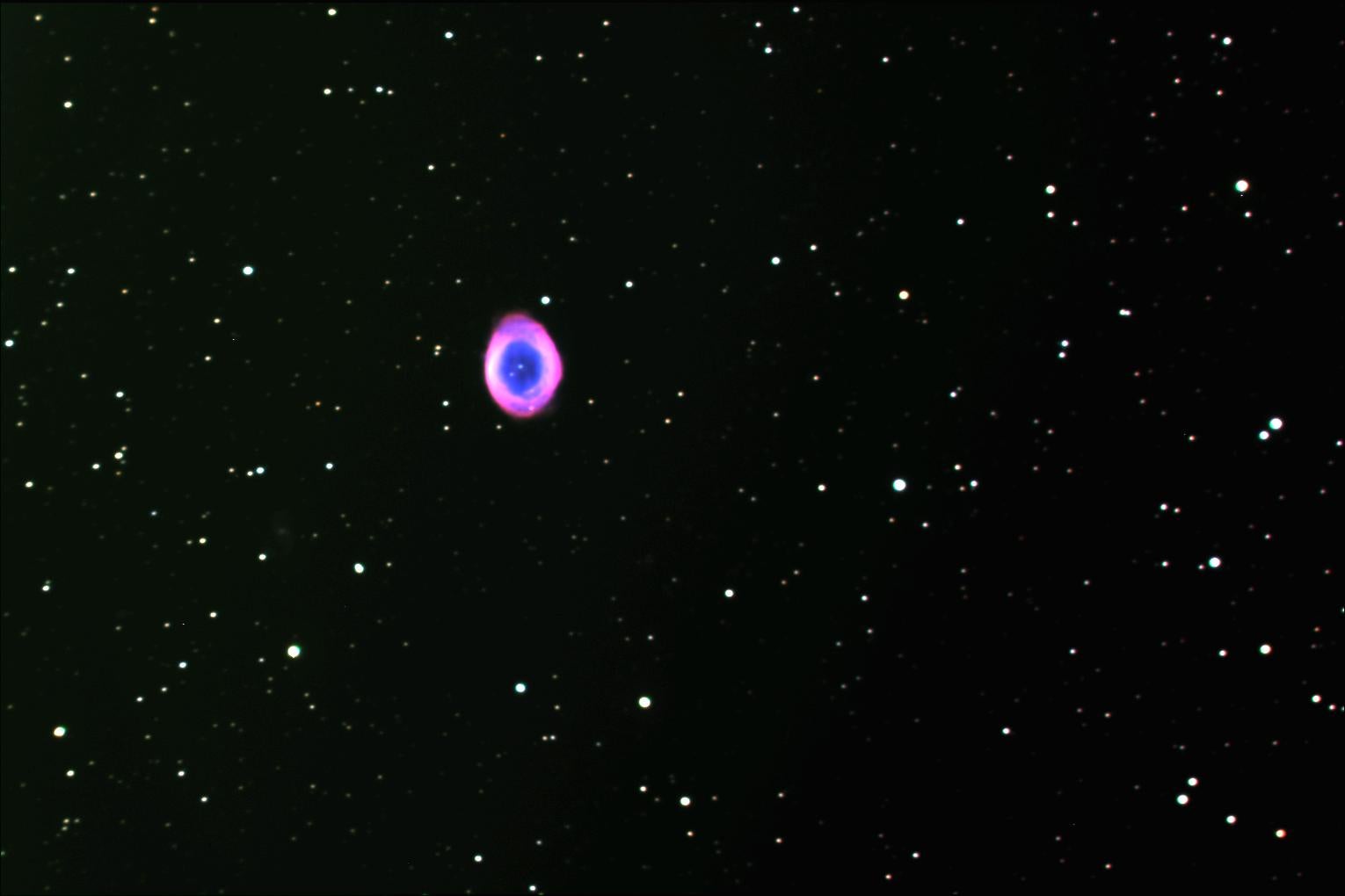 A starry sky with a pink and blue orb in the center